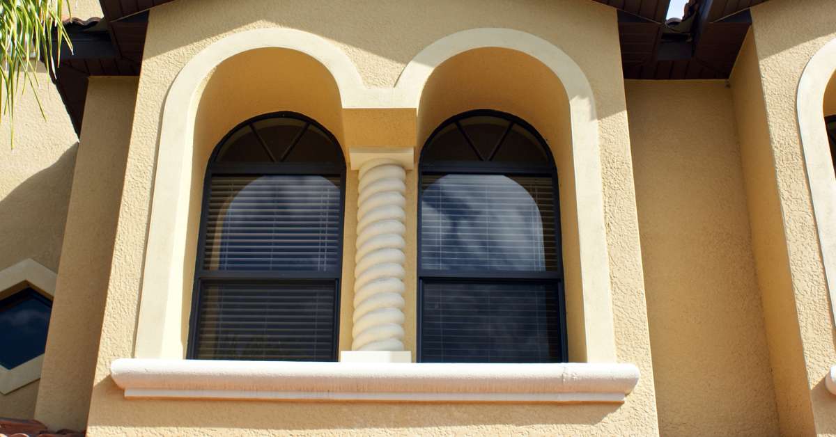 a room with an arched window, adorned with blinds.